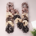 12pc satin silk scrunchies variety pack arranged in N shape with green plant